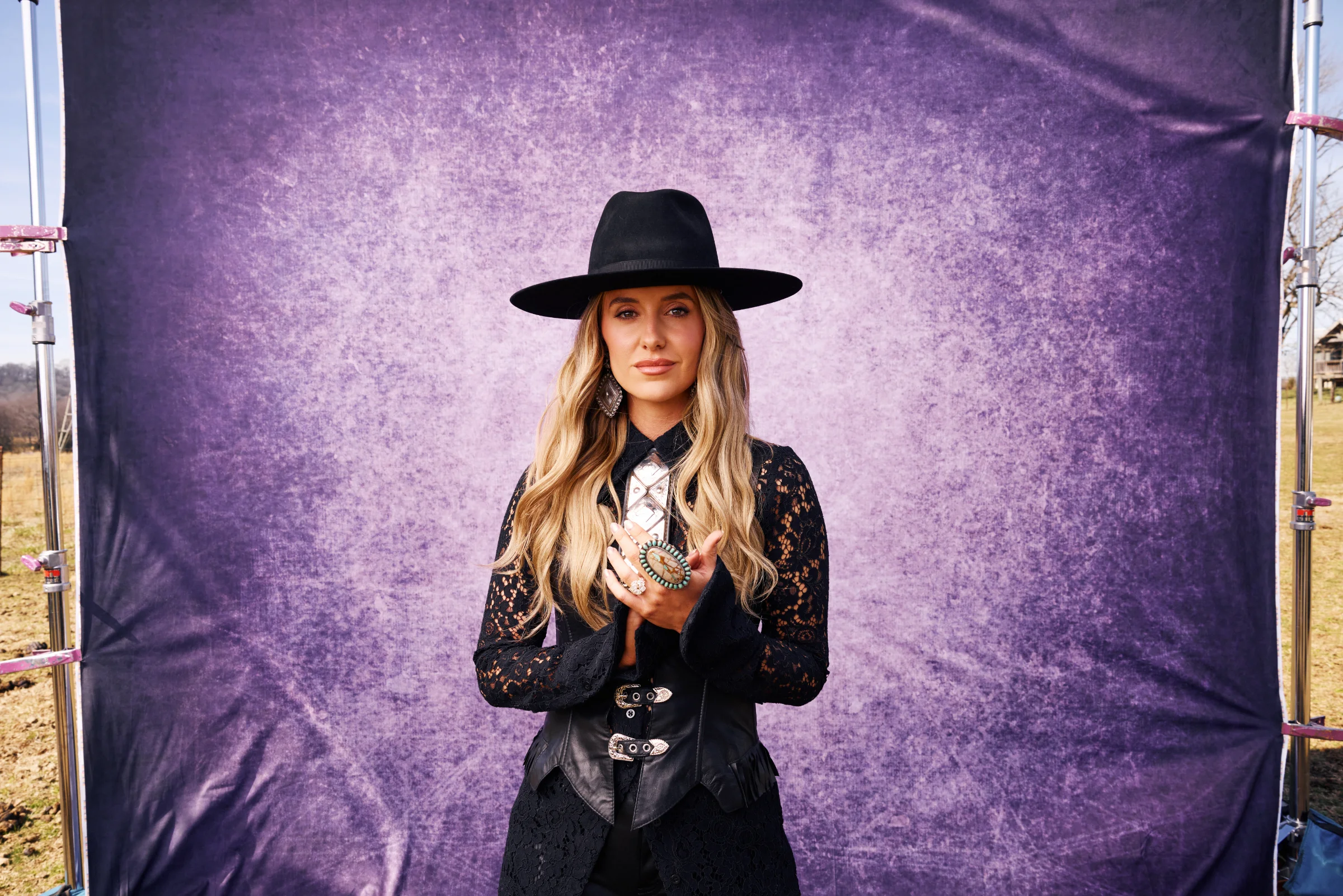 Country Music Singer Lainey Wilson stands in-front of a purple drop