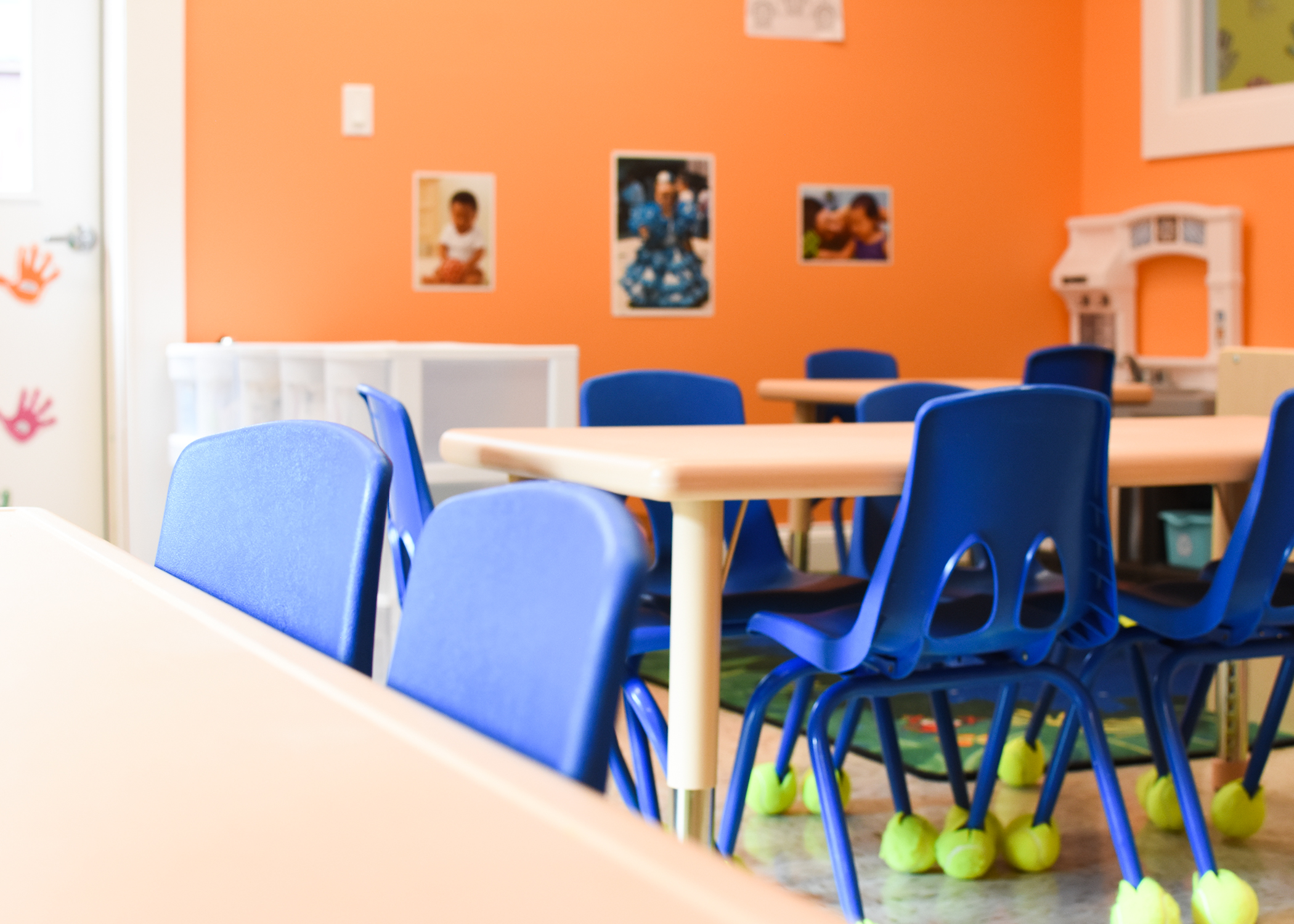Preschool chairs and tables in an orange preschool classroom.
