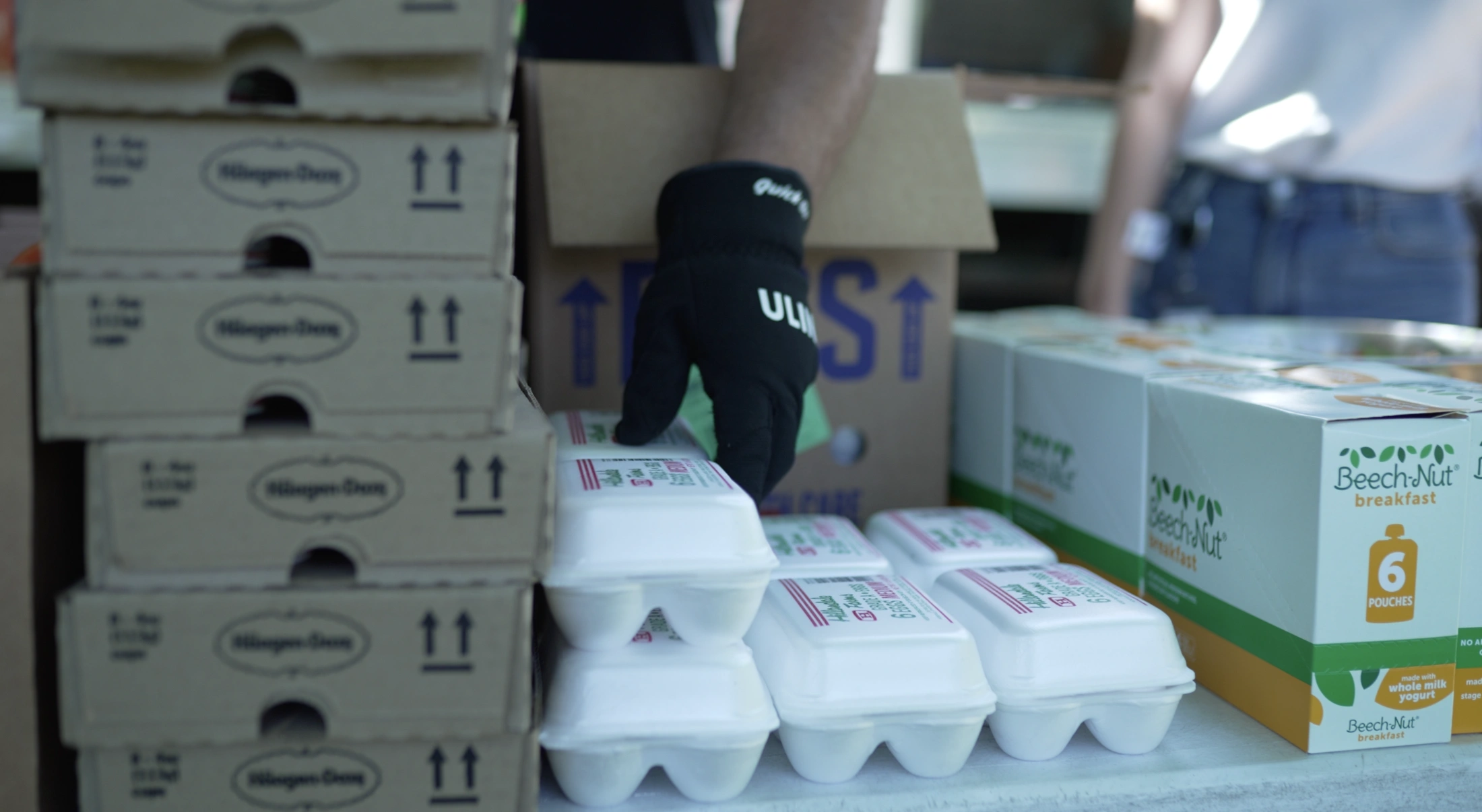 Volunteers load egg cartons on a donation table at a mobile market event for Second Harvest