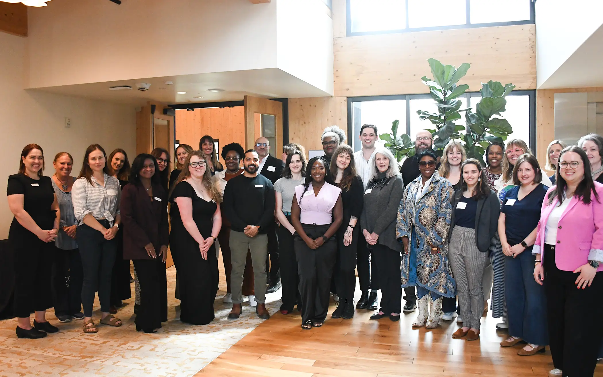A line of members from the Arts and Creative Culture community pose in a line in the CFMT lobby.