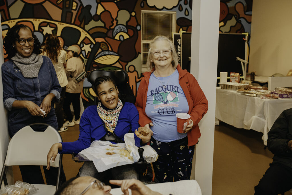Two residents pose with food at an Our Place Super Bowl event.