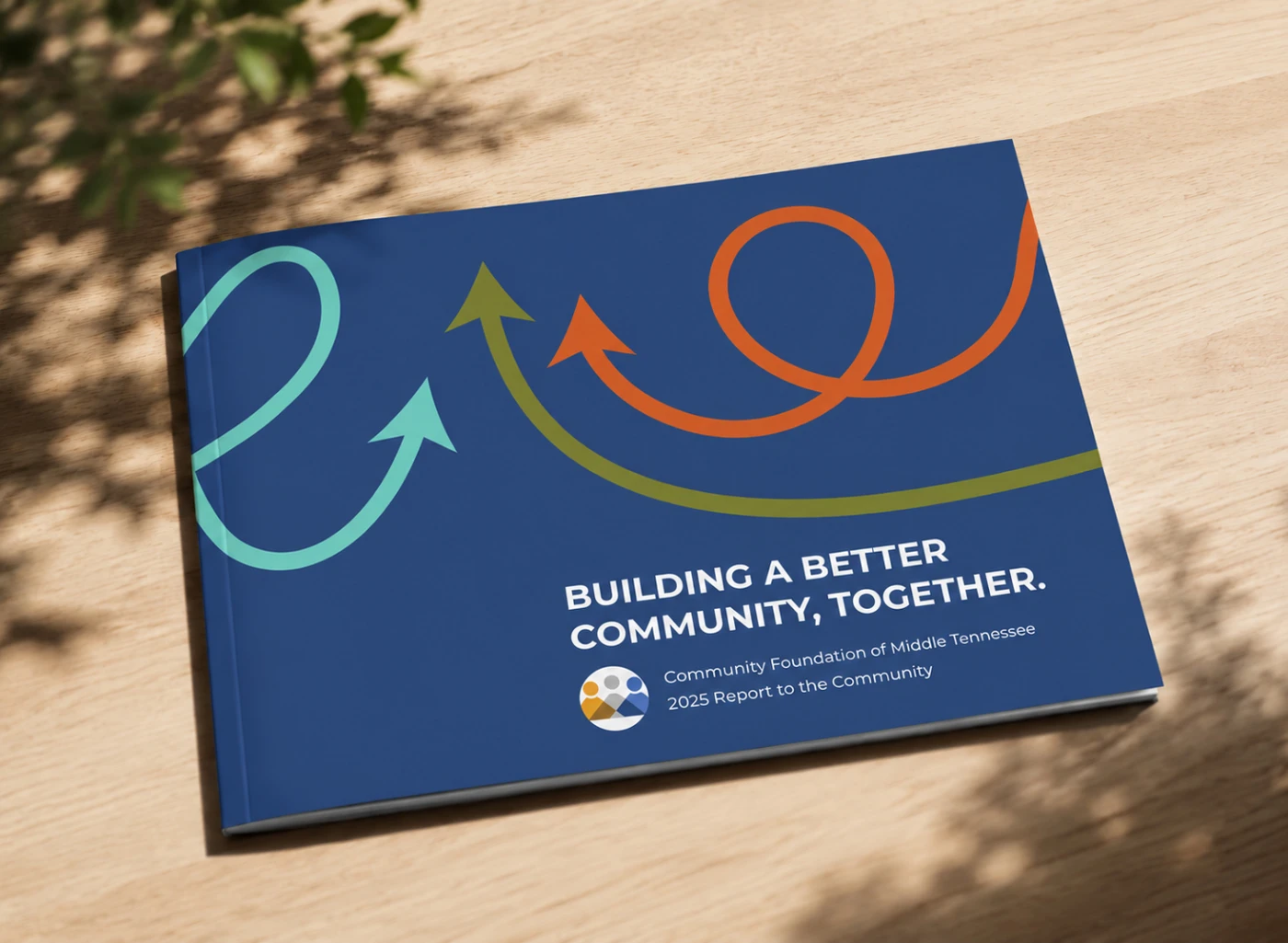 Physical 2025 CFMT Annual Report booklet shown on a wooden table in the sun