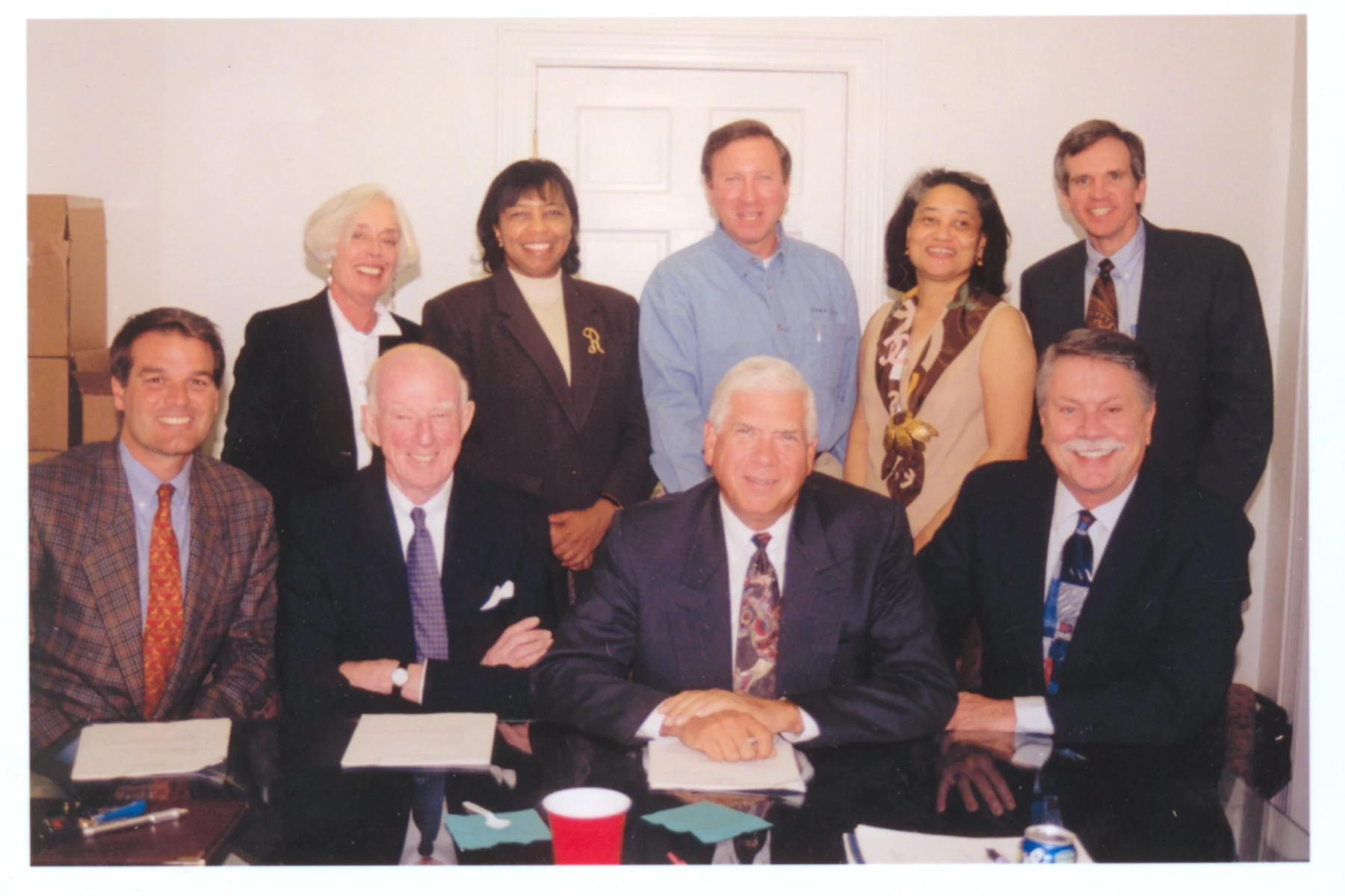 9 early CFMT board members pose for a photo that has a classic old school film grain and sepia hue.