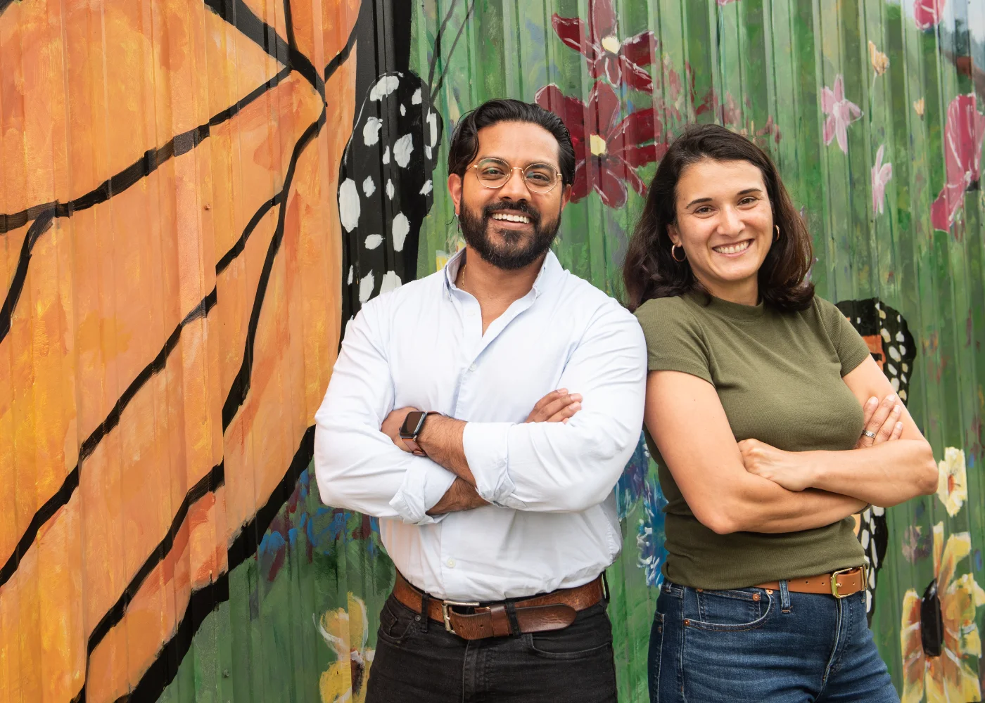 Adnan Karim and Lisa Sherman Luna stand shoulder to shoulder in front of an art mural.