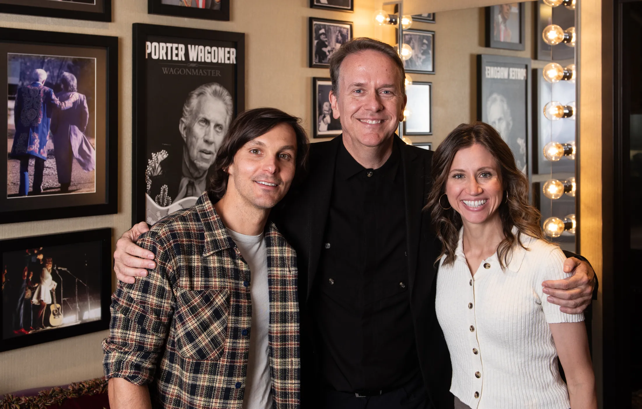 Rondal Richardson stands in a green room with Kristen and Charlie Worsham in front of a wall of images and posters.