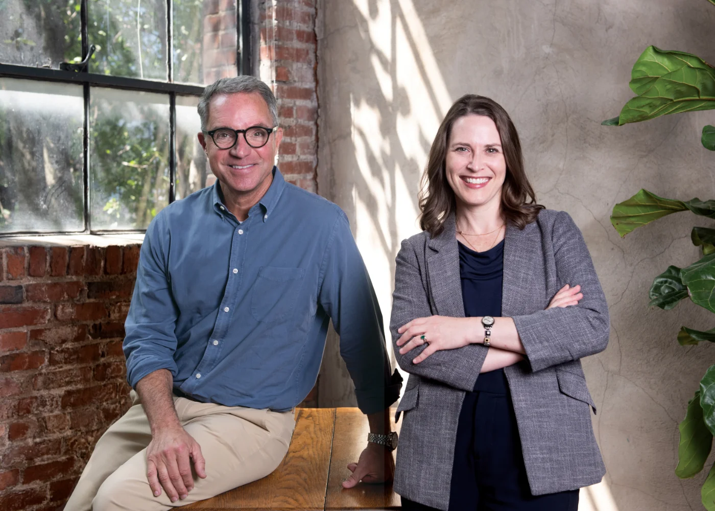 Hal Cato, leans on a wooden desk next to Stephanie Coleman.