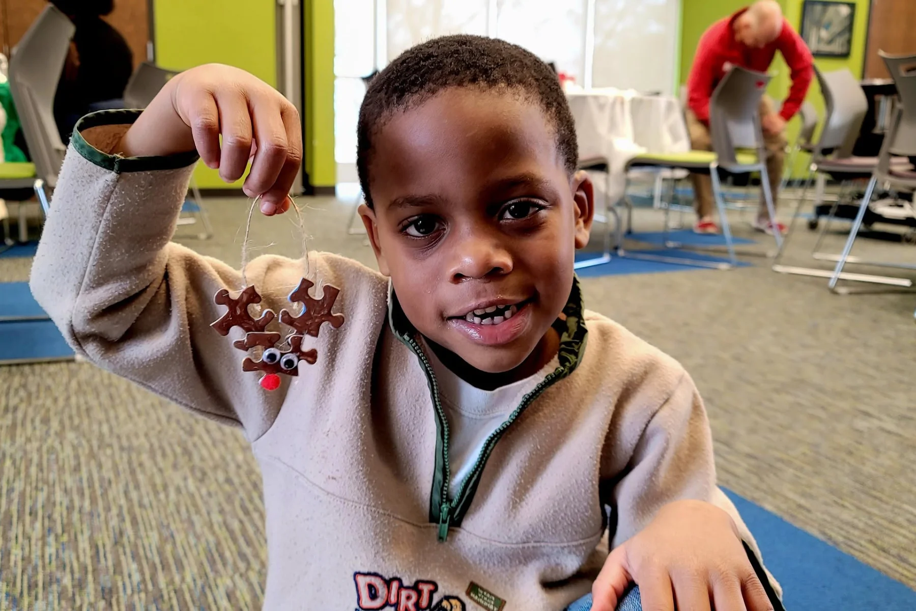 A young boy holds up a Christmas Rudolph decoration inside a learning center.