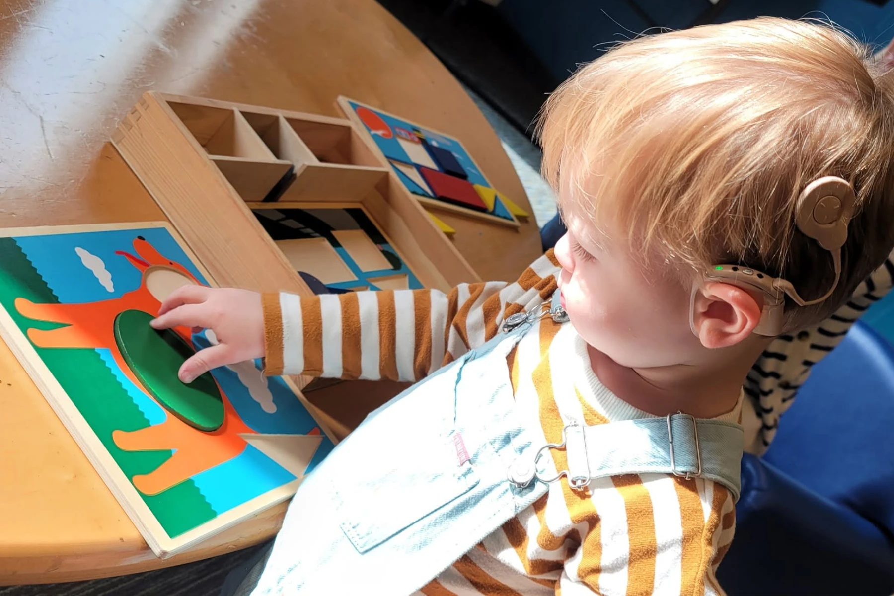 A young boy engages with a puzzle template in a classroom.