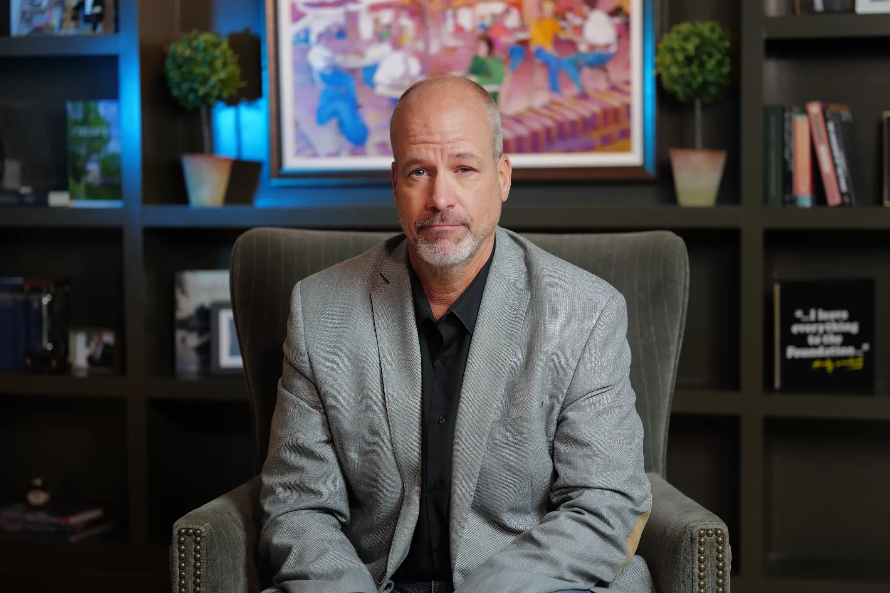 Mike Helms, Vice President of Adult Education and Outreach, sits at his desk in front of a wall of bookshelves.